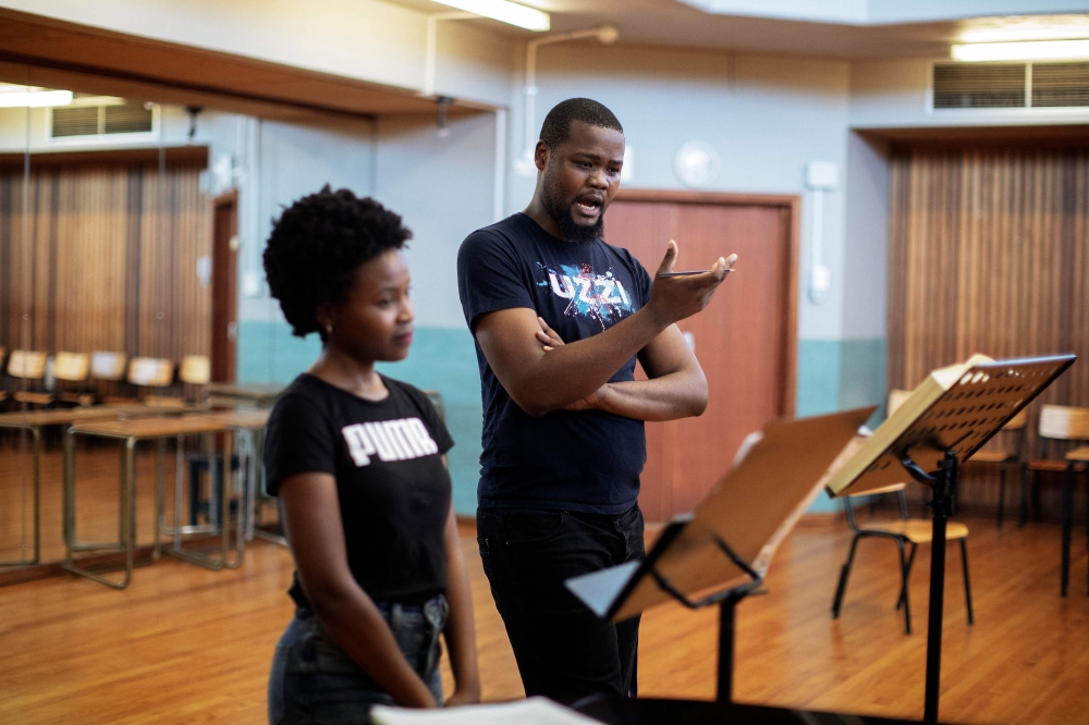 Final year graduate opera student Yonwaba Mbo (C) and first year post graduate opera student Siphosihle Letsoso (L) practice during a rehearsal of Mozart's Le Nozze Di Figaro at the University of Cape Town (UCT) School of Music in Cape Town on November 15, 2023. Photo by GIANLUIGI GUERCIA / AFP