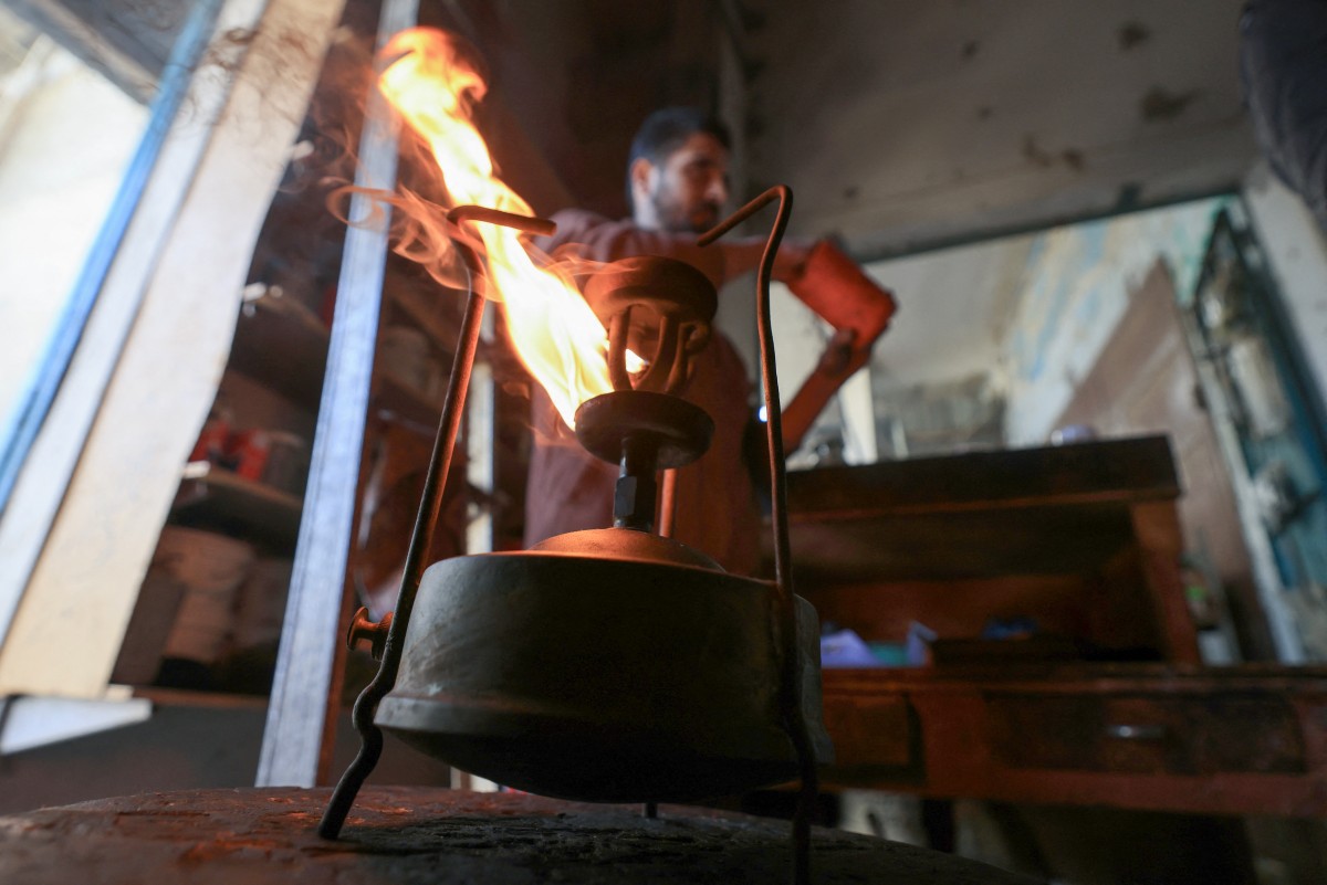 A shopkeeper lights a kerosene pressure stove in Rafah in the southern Gaza Strip on December 9, 2023. (Photo by Mahmud Hams / AFP)
