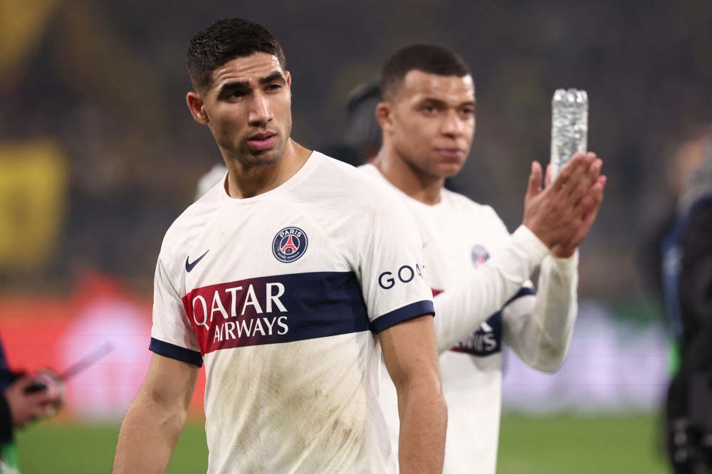 Paris Saint-Germain's French forward #07 Kylian Mbappe (R) and Paris Saint-Germain's Moroccan defender #02 Achraf Hakimi react after the UEFA Champions League group F football match between BVB Borussia Dortmund and Paris Saint-Germain in Dortmund, western Germany, on December 13, 2023. (Photo by FRANCK FIFE / AFP)