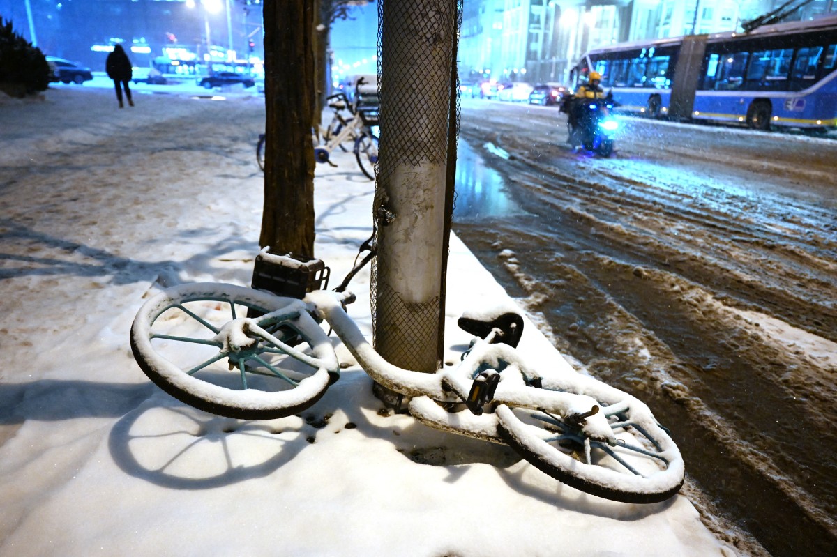 A snow-covered bicycle lies on a sidewalk during a snowfall in Beijing on December 14, 2023. (Photo by GREG BAKER / AFP)
