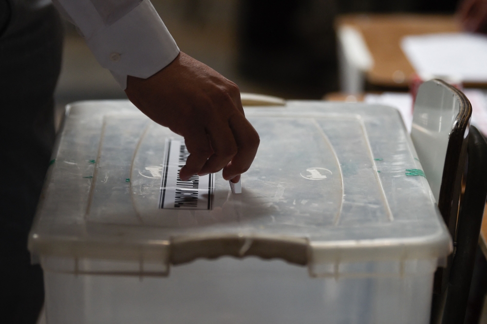 A man casts his vote during the referendum for Chile's new constitution proposal, in Santiago, on December 17, 2023. (Photo by Pablo Vera / AFP)
