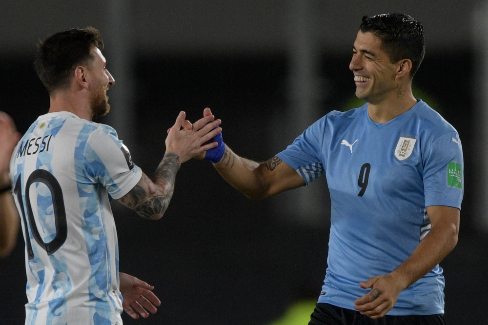 (FILES) Argentina's Lionel Messi (L) greets Uruguay's Luis Suarez before the start of the South American qualification football match for the FIFA World Cup Qatar 2022, at the Monumental stadium in Buenos Aires, on October 10, 2021. (Photo by Juan Mabromata / AFP)