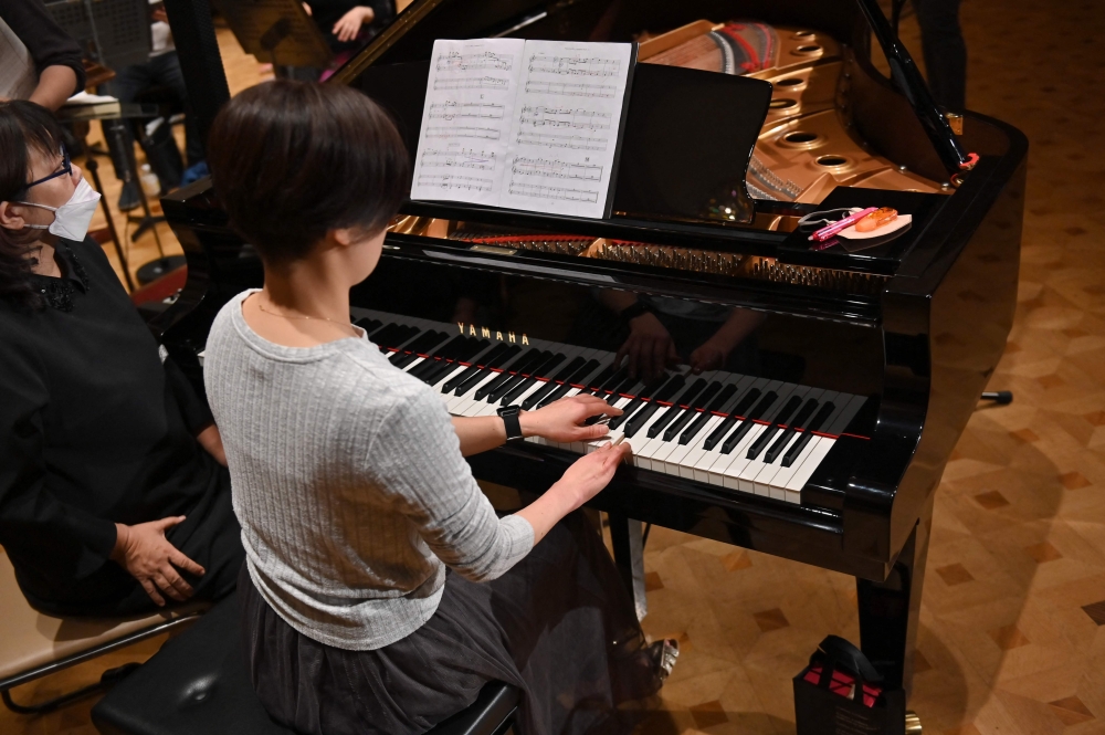 This picture taken on December 20, 2023 shows Hiroko Higashino (C) playing an AI-powered piano during a Christmas concert rehearsal of Beethoven Symphony No 9 with the Yokohama Sinfonietta orchestra in Tokyo. (Photo by Kazuhiro Nogi / AFP)