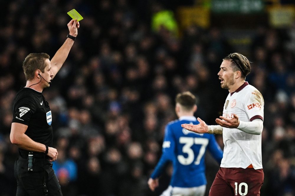 Manchester City's English midfielder #10 Jack Grealish (R) reacts as he receives a yellow card during the English Premier League football match between Everton and Manchester City at Goodison Park in Liverpool, north west England on December 27, 2023. (Photo by Paul ELLIS / AFP