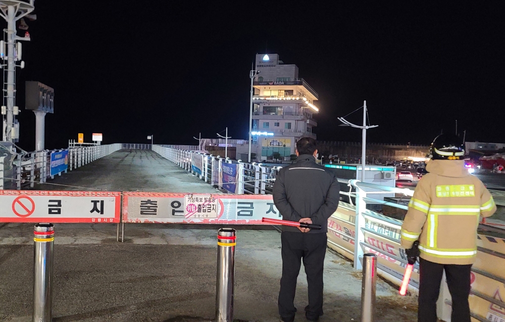 South Korean emergency workers patrol in front of a seawall with a 