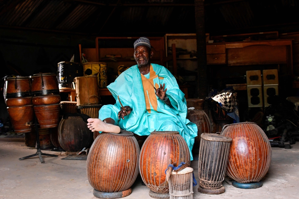Oumarou Adamou, alias “Maïdouma”, a traditional Nigerien percussionist artist, player and manufacturer of membranophone instruments, makes music in his workshop located within the Professional Music Training Center (CFPM) in Niamey, on October 25, 2023. (Photo by Boureima Hama / AFP)