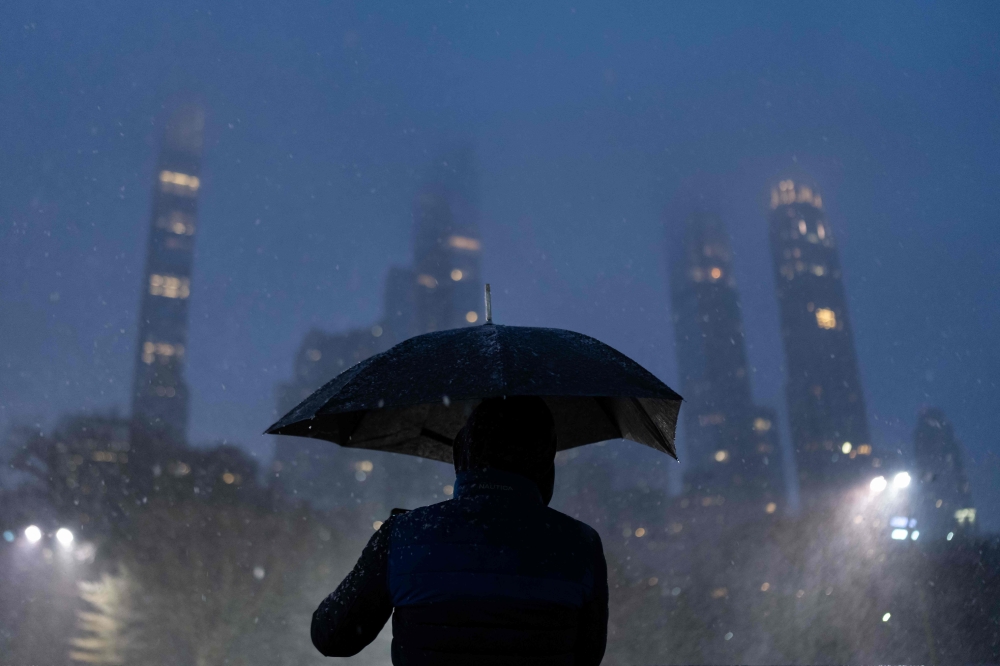 A person takes a photograph of snowfall in Central Park in New York City on January 6, 2024. Photo by Adam GRAY / AFP
