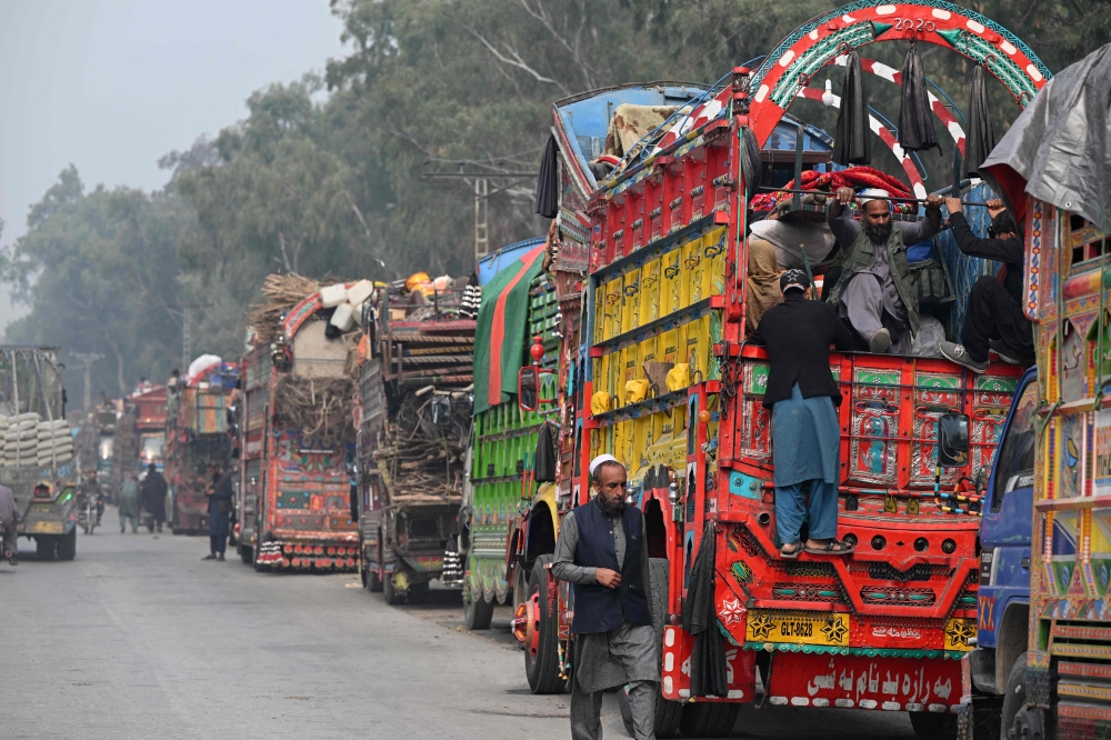 This photo taken on November 23, 2023 shows Afghan refugee on a truck after visiting the United Nations High Commissioner for Refugees (UNHCR) Azakhel Voluntary Repatriation Centre in Nowshera. More than 345,000 Afghans have returned to their country or been deported since Pakistan in October ordered undocumented migrants or those who have overstayed their visas to leave. (Photo by Farooq Naeem / AFP)