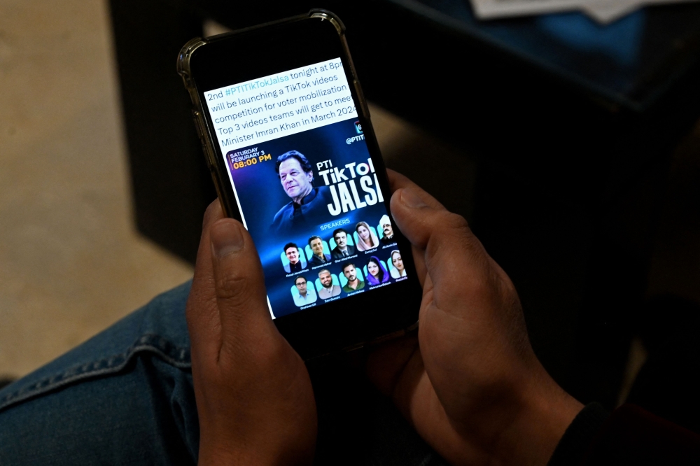 Pakistan's former prime minister Imran Khan's supporter listens to a virtual election campaign on a phone at Khan's PTI office in Islamabad on February 3, 2024. (Photo by Aamir Qureshi / AFP)

