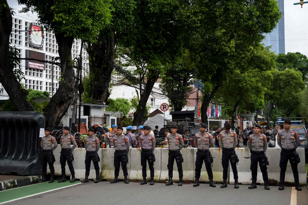 Police secure a road as a group of people supporting presidential candidate Anies Baswedan takes part in a rally in front of the General Election Commission (KPU) in Jakarta on February 16 2024, and demand that the KPU reveal fraud committed by presidential candidate Prabowo Subianto, who also won the quick count version of the presidential election and was supported by incumbent President Joko Widodo. (Photo by BAY ISMOYO / AFP)
