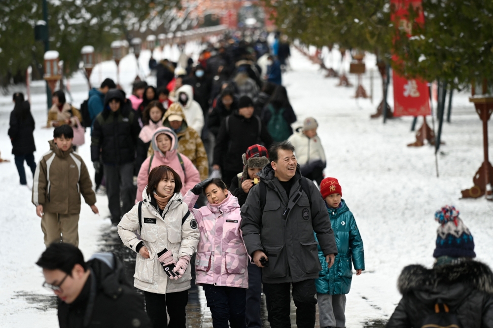 People visit the Temple of Heaven after snowfall in Beijing on February 21, 2024. (Photo by WANG Zhao / AFP)