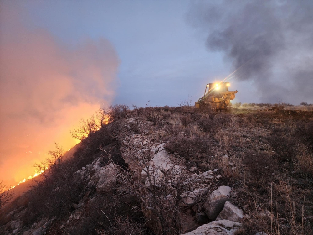 This handout picture courtesy of the Texas A&M Forest Service and taken on February 27, 2024, shows a Texas A&M Forest Service bulldozer building a containment line as it battles the Windy Deuce Fire in Moore County, Texas. (Photo by J. Griffin / Texas A&M Forest Service / AFP)