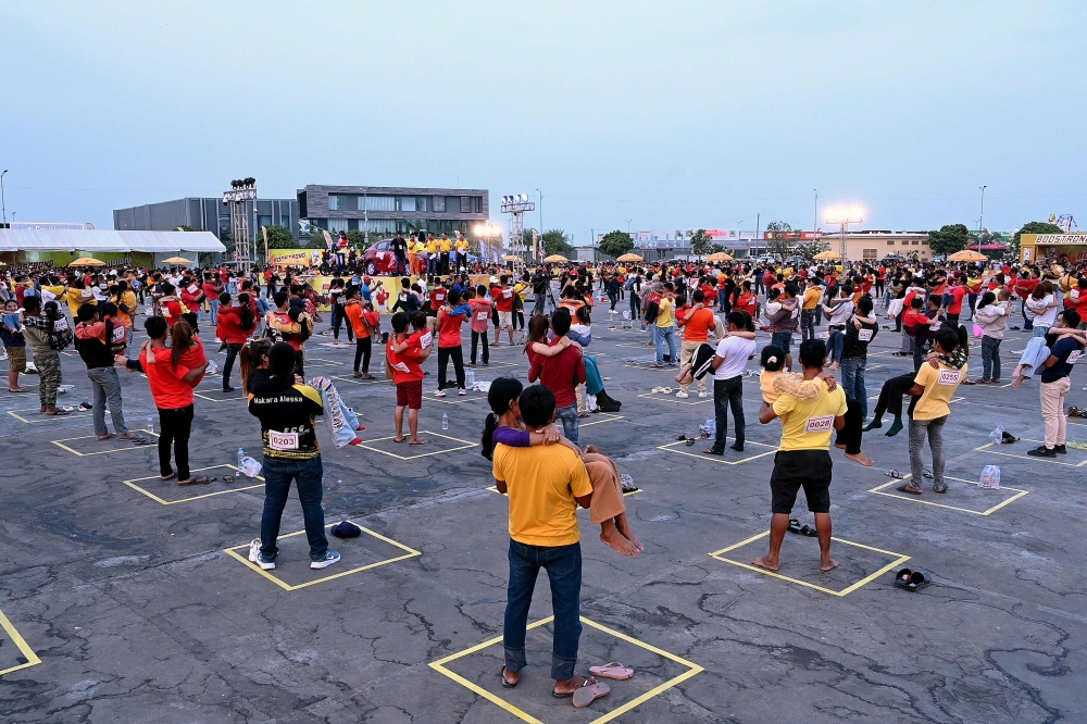 Men carry women as a test ahead of a competition and Guinness World Record attempt in Phnom Penh on March 8, 2024. (Photo by Tang Chhin Sothy / AFP)