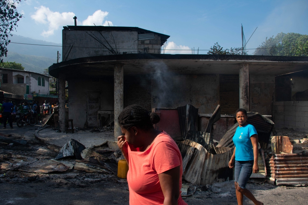 A woman cries as she walks near her husband's shop that armed gang members set fire to in Port-au-Prince, Haiti, March 7, 2024. (Photo by clarens SIFFROY / AFP)