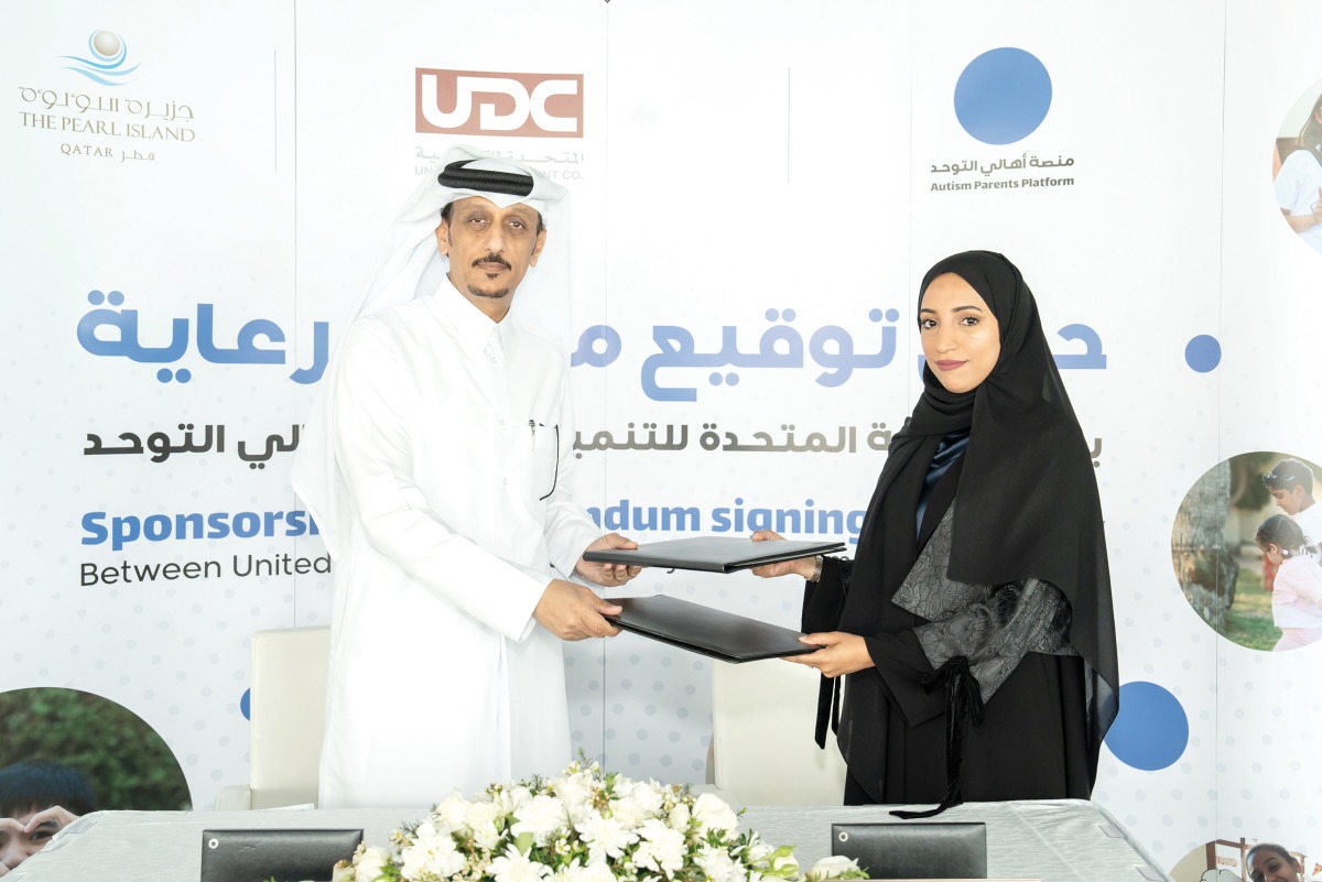 UDC Executive Director of Public Services Abdullatif Ali Al-Yafei and Founder of the Autism Parents Platform Hamda Al-Hitmi exchanging documents after signing the agreement.