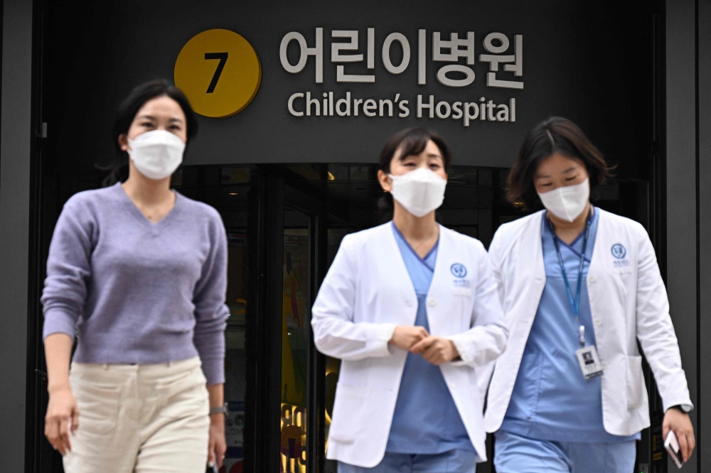 Medical workers walk outside a children's hospital in Seoul on March 11, 2024. (Photo by ANTHONY WALLACE / AFP)