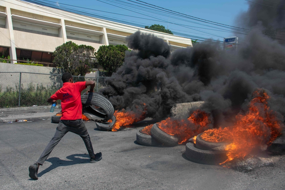 A protester burns tires during a demonstration following the resignation of its Prime Minister Ariel Henry, in Port-au-Prince, Haiti, on March 12, 2024. (Photo by Clarens Siffroy / AFP)
