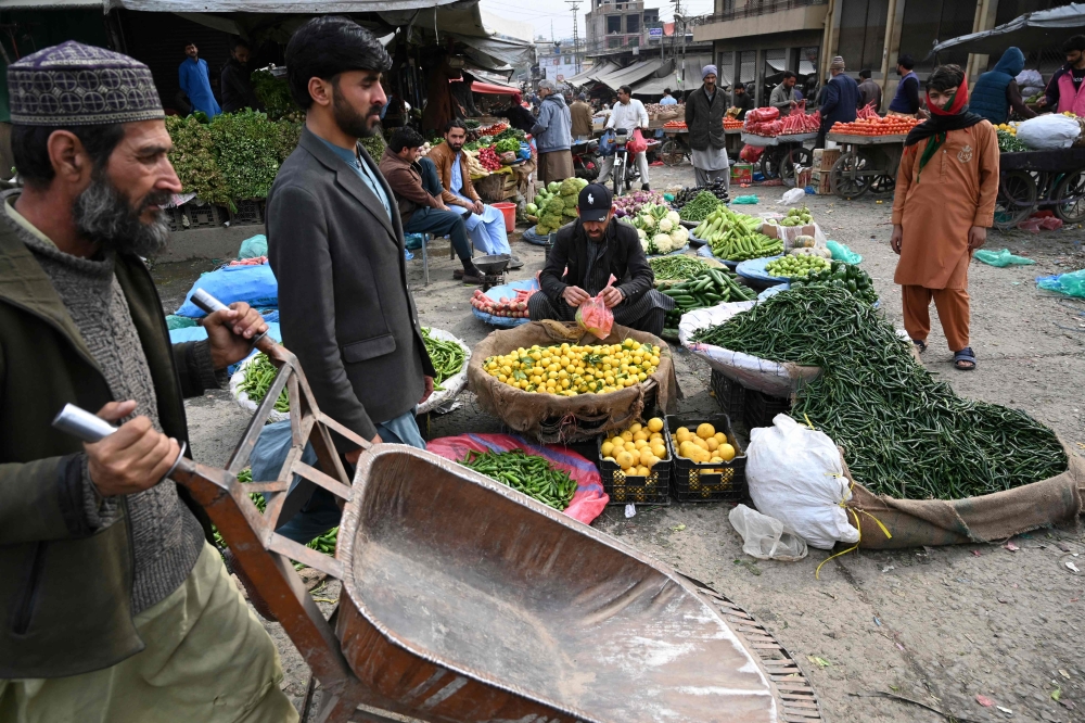 File: People buy vegetable at a market in Islamabad on February 3, 2023. - Pakistan's Prime Minister Shehbaz Sharif said February 3 the government would have to agree to IMF bailout conditions that are 
