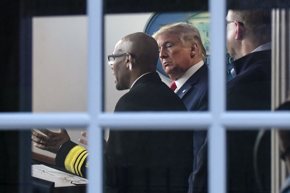 :(FILES) US President Donald Trump (R) listens as US Surgeon General Jerome Adams speaks during the daily briefing on the novel coronavirus, COVID-19, at the White House on March 22, 2020, in Washington, DC. (Photo by Eric BARADAT / AFP)
