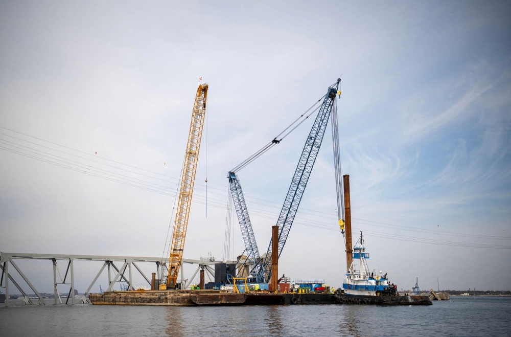 This handout photo obtained from the US Coast Guard on March 31, 2024 shows barge cranes near the collapsed Francis Scott Key Bridge on in the Patapsco River, in Baltimore, Maryland, March 30, 2024. (Photo by Taylor BACON / US COAST GUARD / AFP)