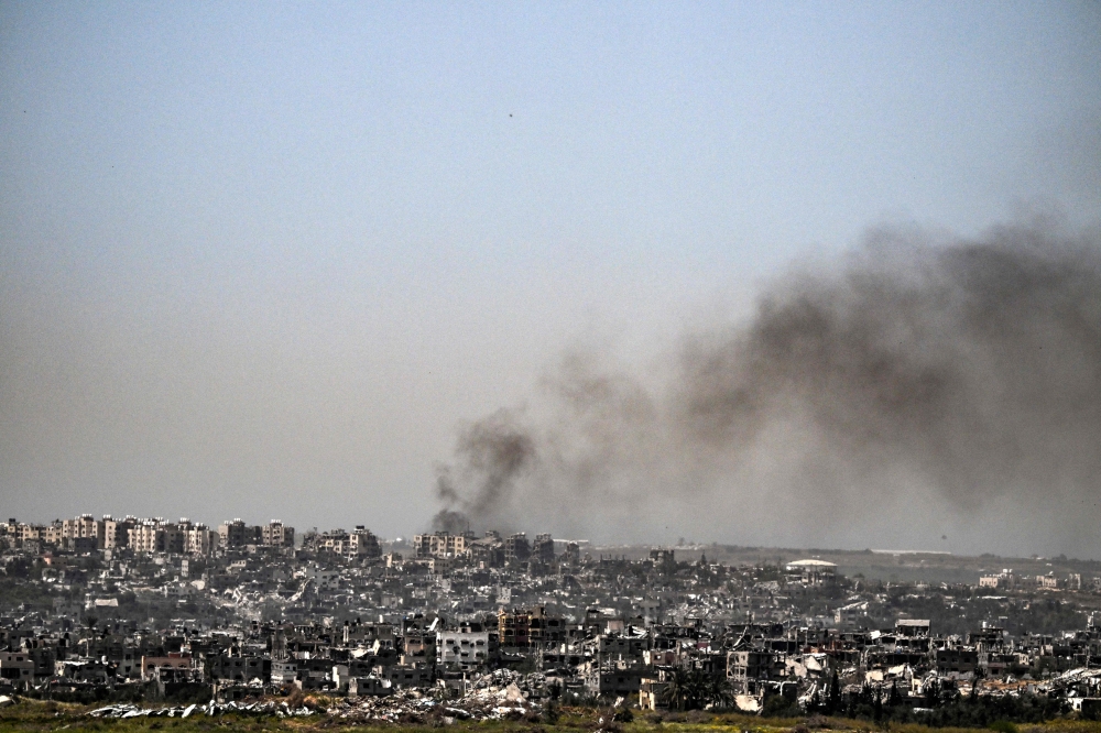 This picture taken from Israel's southern border with the Gaza Strip shows smoke billowing behind destroyed buildings due to Israeli strikes on the besieged Palestinian territory on April 2, 2024. (Photo by RONALDO SCHEMIDT / AFP)
