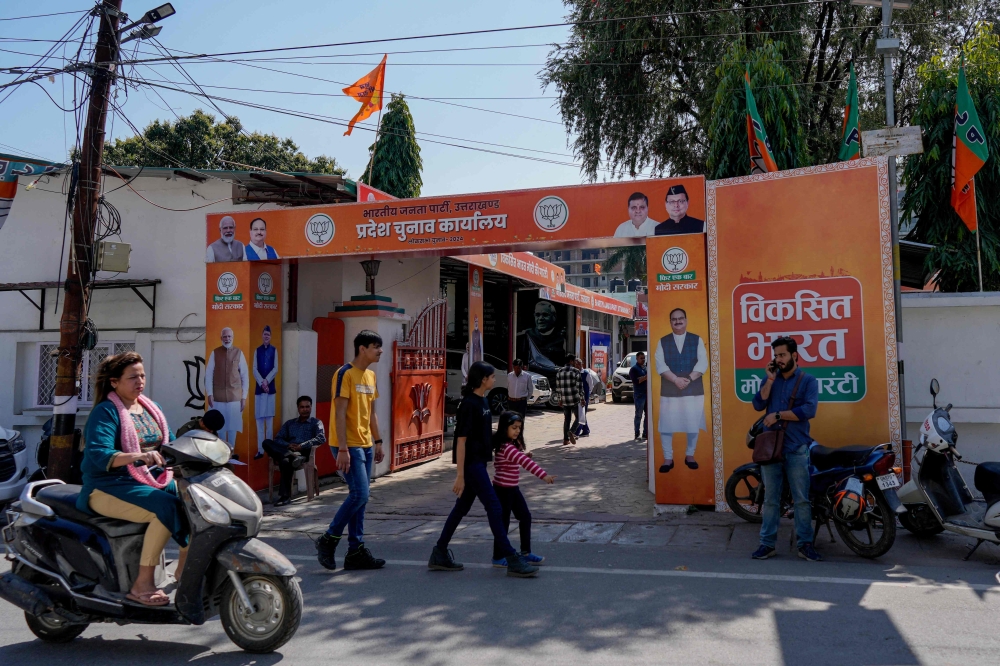 This photograph taken on March 19, 2024 shows people walking past the ruling Bharatiya Janata Party (BJP) office in Dehradun, in India's Uttarakhand state. (Photo by Amarjeet Kumar Singh / AFP)