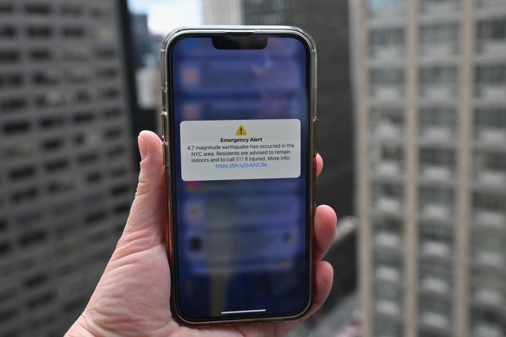  A phone shows an Emergency Alert message on April 5, 2024, warning of an earthquake in New York. Photo by ANGELA WEISS / AFP.