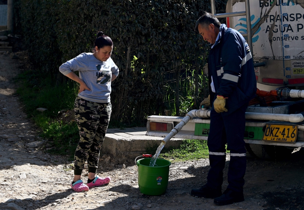 A  woman collects drinking water from a water truck in La Calera, near Bogota, April 10, 2014. (Photo by AFP)
 
