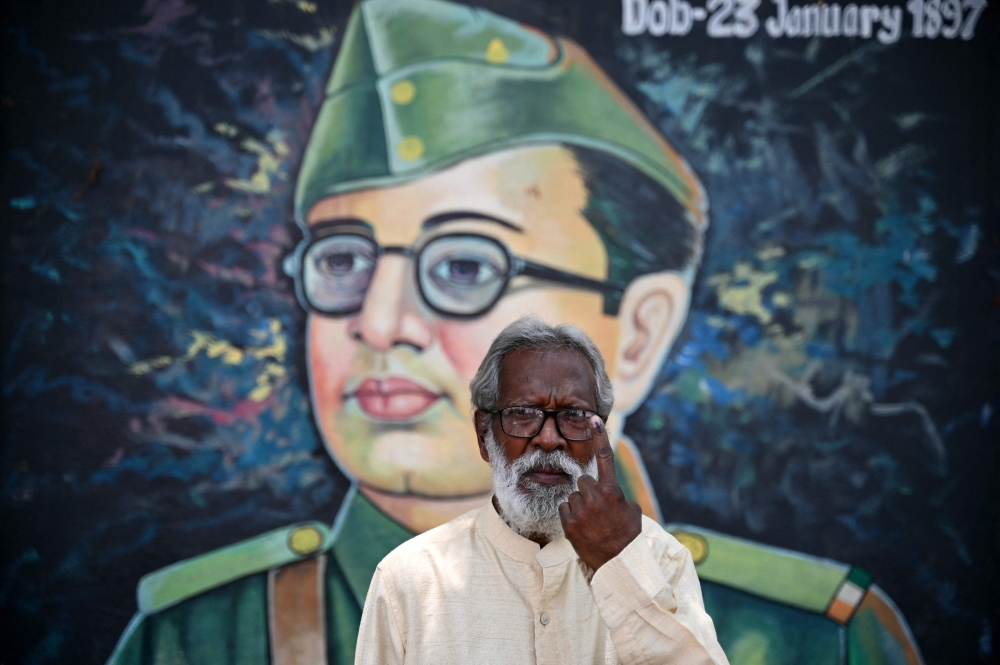 Jaganadhan, a 62-old-year man, poses for a picure in front of a mural Indian revolutionary Subhas Chandra Bose as he shows his inked finger after casting his ballot during the second phase of voting in India's general election, in Bengaluru on April 26, 2024. Photo by Idrees MOHAMMED / AFP