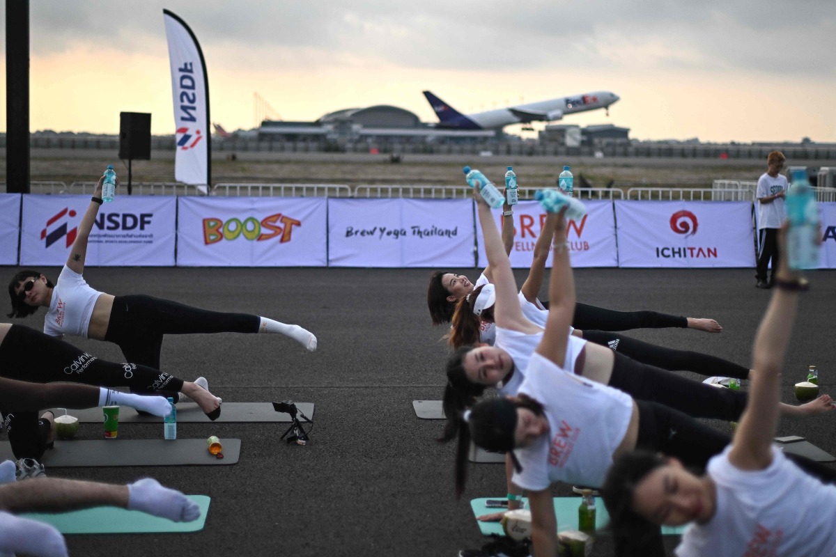 Yoga enthusiasts perform yoga during a sunrise 