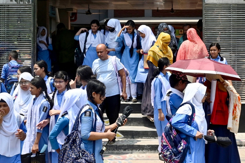 Students leaving their school compound carry umbrellas on a hot summer day in Dhaka on April 28, 2024. (Photo by Munir UZ ZAMAN / AFP)
 