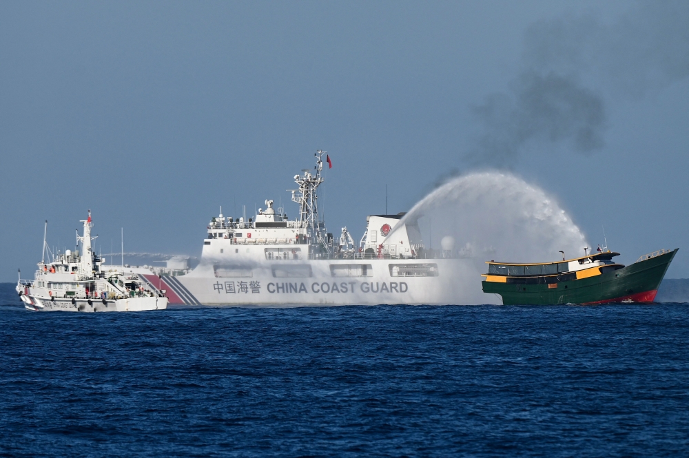 (Files) This photo taken on March 5, 2024 shows China Coast Guard vessels deploying water cannons at the Philippine military chartered Unaizah May 4 (R) during its supply mission to Second Thomas Shoal in disputed waters of the South China Sea. (Photo by Jam Sta Rosa / AFP)
 