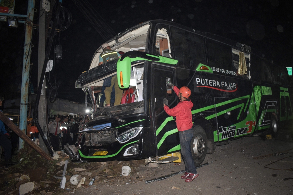 Officers check the damaged bus after a crash that killed 11 people, according to local police, in Subang, West Java, on May 11, 2024. (Photo by Timur Matahari / AFP)