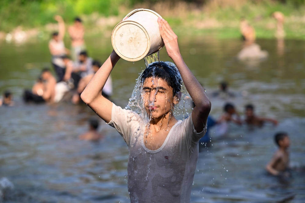 Boys bathe in the waters of Rawal dam on a hot summer day in Islamabad on May 23, 2024. The Pakistan Meteorological Department said temperatures are expected to hit as high as 50 degrees Celsius (122 degrees Fahrenheit) in parts of rural Sindh. Photo by FAROOQ NAEEM / AFP.