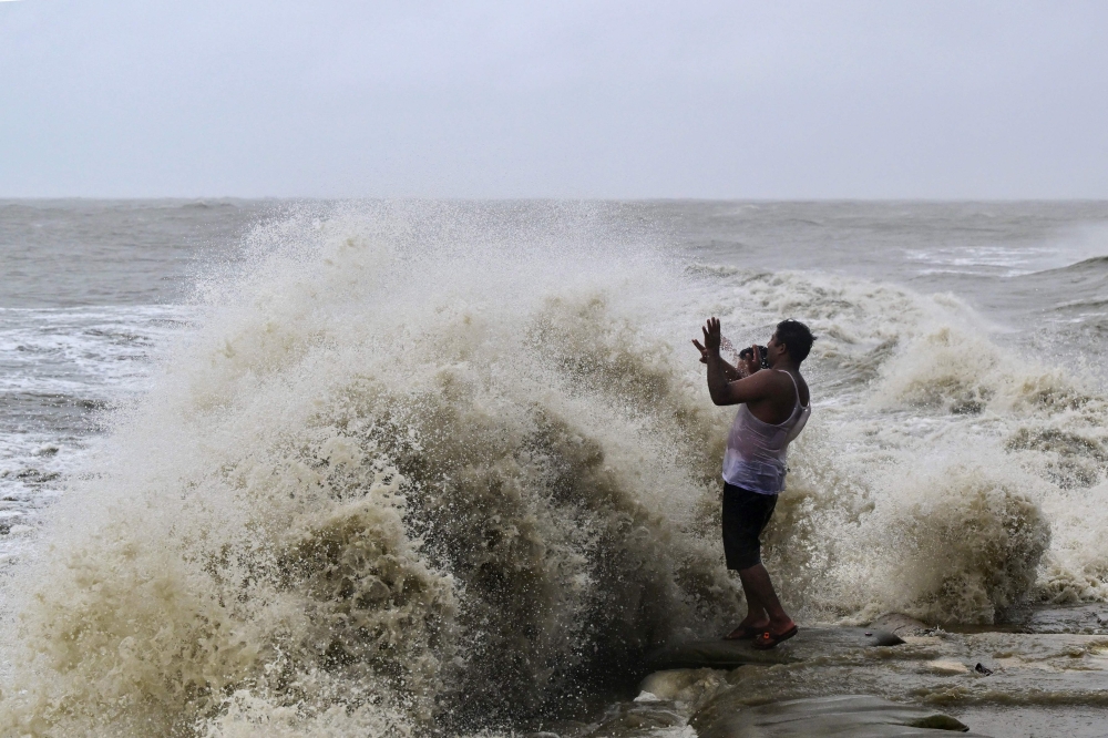 A man reacts as high tidal waves hit the coast along a sea beach during rainfall in Kuakata on May 26, 2024, ahead of cyclone Remal's landfall in Bangladesh. (Photo by Munir Uz Zaman / AFP)