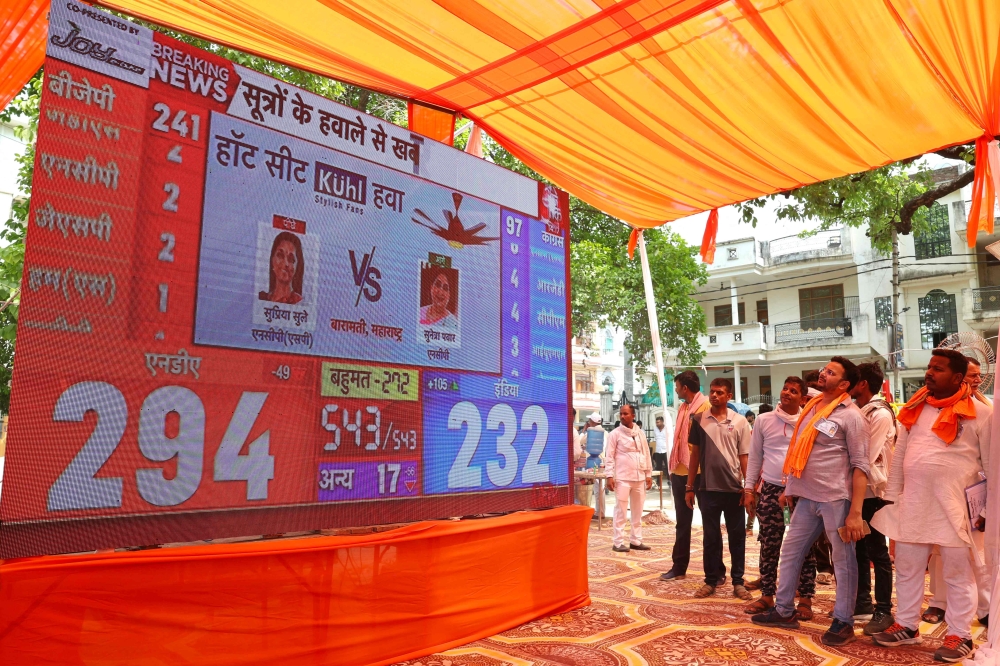 Supporters of the Bharatiya Janata Party (BJP) watch live vote counting figures for India's general election, displayed on a large screen in Varanasi on June 4, 2024. (Photo by Niharika Kulkarni / AFP)