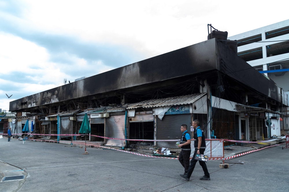 Forensics officers survey the area after a fire at a pet market next to Chatuchak market in Bangkok on June 11, 2024. (Photo by Chanakarn Laosarakham / AFP)