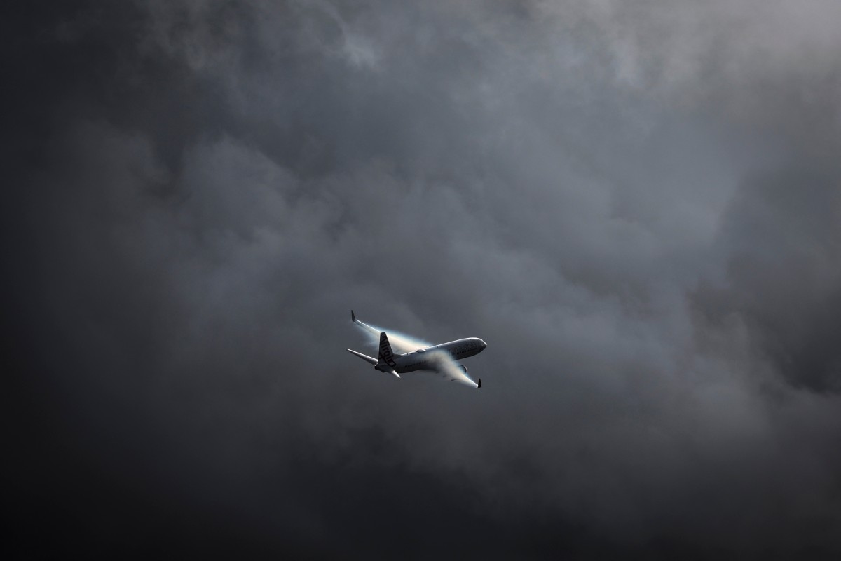 A Virgin Australia Airlines Boeing 737 plane flies as a storm approaches at Sydney International Airport on June 7, 2024. Photo by DAVID GRAY / AFP.