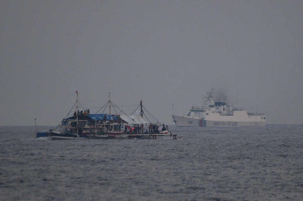 A China Coast Guard ship (R) sailing past a Philippine fishing boat with volunteers from the civilian-led mission Atin Ito (This Is Ours) Coalition on board, in the disputed South China Sea on May 15, 2024. (Photo by Ted ALJIBE / AFP)
