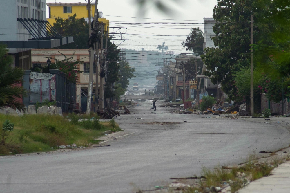 A person runs after stealing equipment from stores near the National Palace in Port-au-Prince, Haiti, on June 28, 2024. (Photo by Clarens SIFFROY / AFP)
