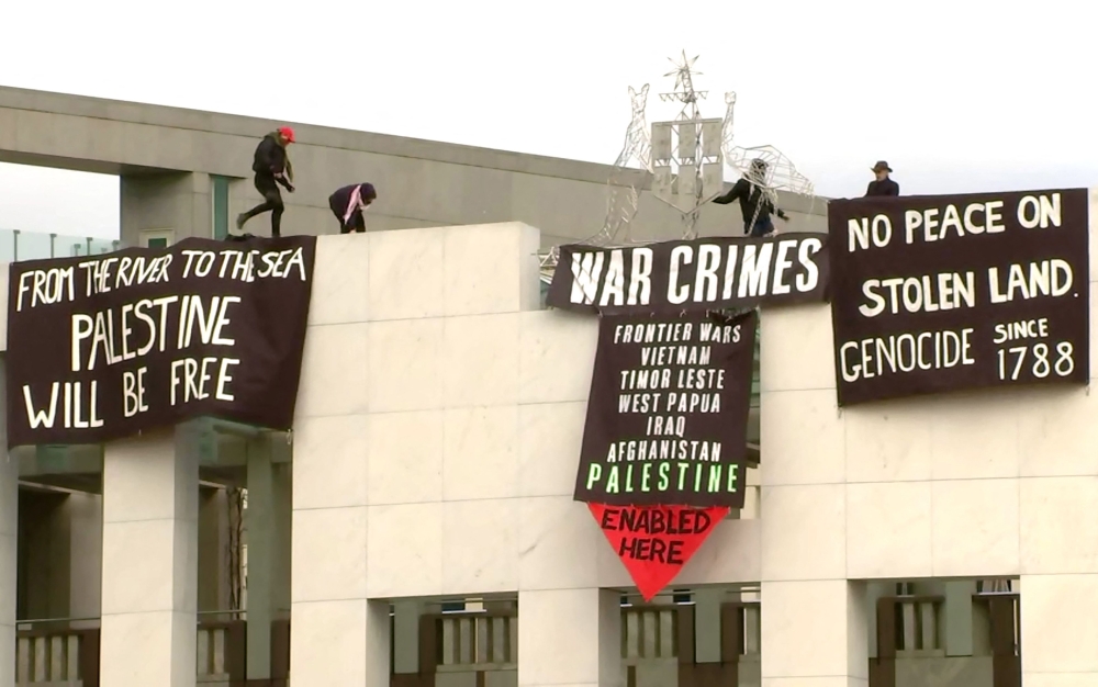 This frame grab taken from video footage provided by Australian Broadcast Corporation (ABC) on July 4, 2024, shows protesters with banners above the main entrance to Parliament House in Canberra. (Photo by Australian Broadcast Corporation (ABC) / AFP) 