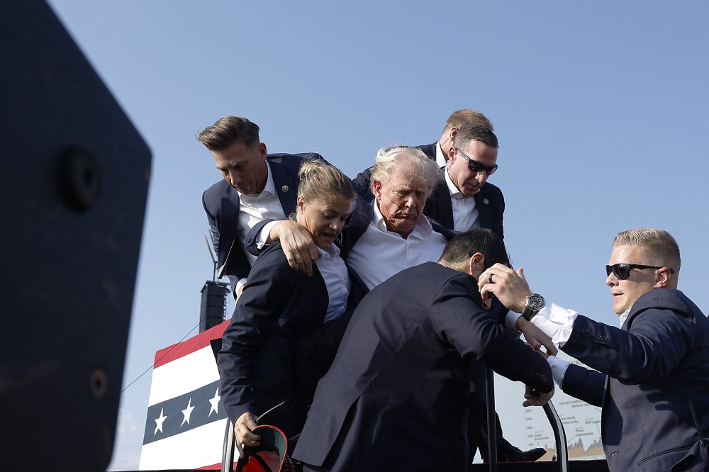  Republican presidential candidate former President Donald Trump pumps his fist as he is rushed offstage during a rally on July 13, 2024 in Butler, Pennsylvania. (Photo by Anna Moneymaker / GETTY IMAGES NORTH AMERICA / Getty Images via AFP)
