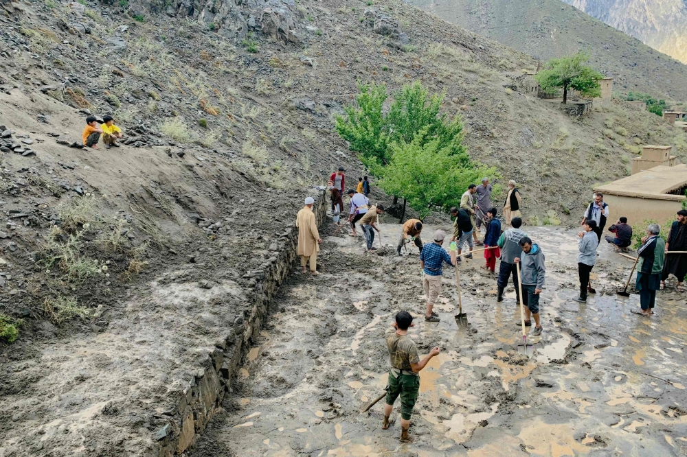 Afghan residents shovel mud following flash floods after heavy rainfall at Pesgaran village in Dara district, Panjshir province on July 15, 2024. At least 35 people were killed and 230 injured on July 15, after heavy rain in eastern Afghanistan, a local official said. (Photo by AFP)
