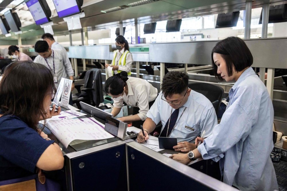 Airport staff manually check-in passengers at Hong Kong International Airport on July 19, 2024, due to a world wide Microsoft outage. (Photo by ISAAC LAWRENCE / AFP)