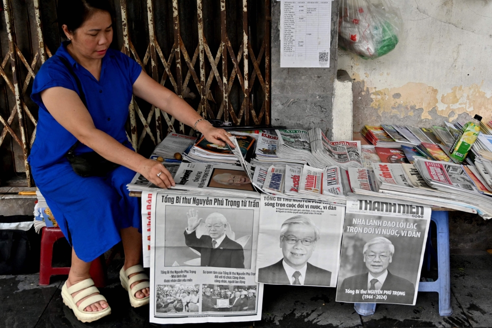 A vendor arranges newspapers reporting on the death of Nguyen Phu Trong, the general secretary of the Communist Party of Vietnam, in Hanoi on July 20, 2024. (Photo by Nhac Nguyen / AFP)