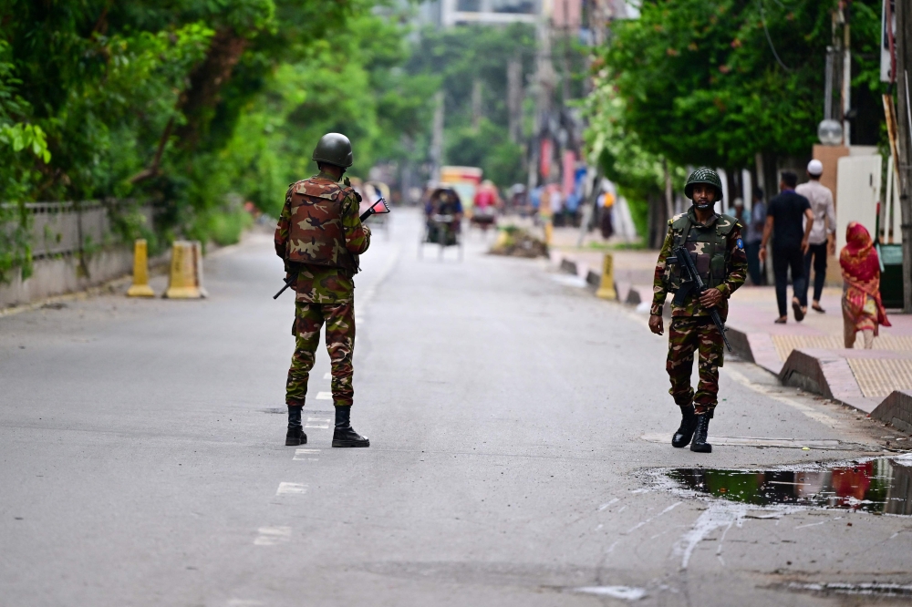 Bangladeshi soldiers stand guard along a street during a curfew amid the anti-quota protests, in Dhaka on July 23, 2024. (Photo by Munir UZ ZAMAN / AFP)
