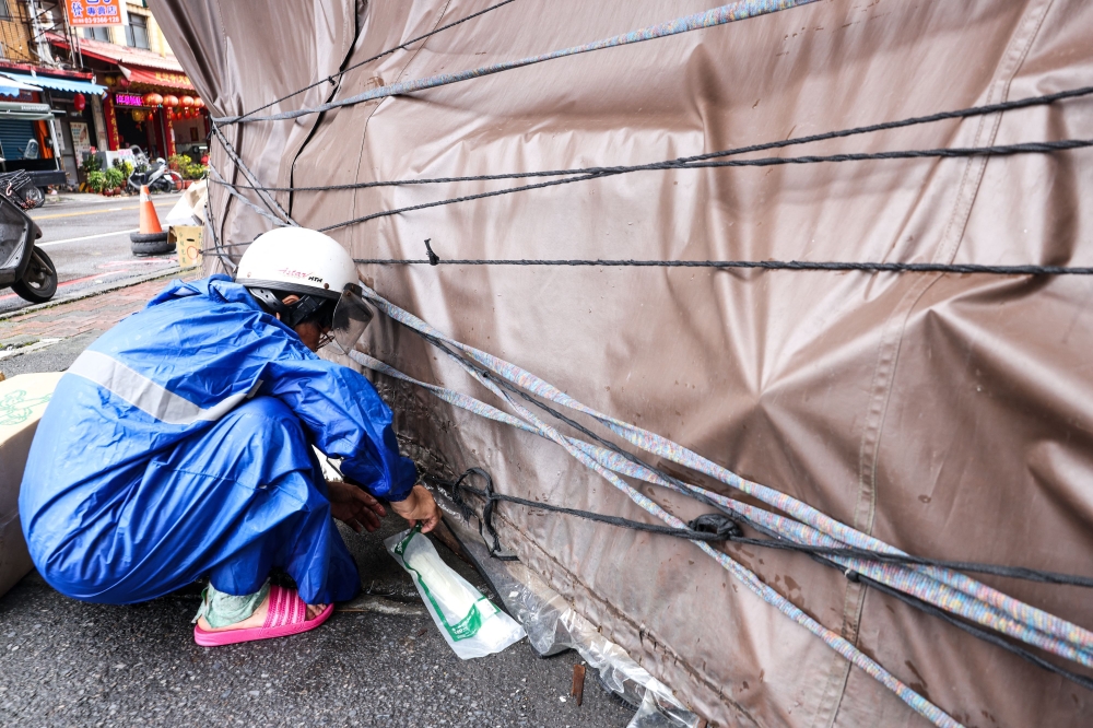 A shop owner tightens canvas around his booth to prevent possible damage as Typhoon Gaemi approaches, in Yilan on July 24, 2024. (Photo by I-Hwa Cheng / AFP)
 