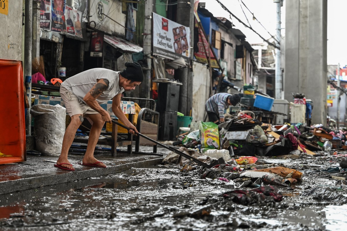 Residents clean their houses in the aftermath of Typhoon Gaemi in Manila on July 25, 2024. (Photo by Jam Sta Rosa / AFP)

