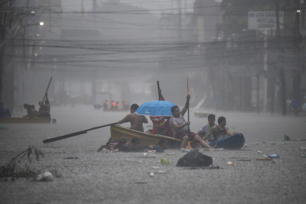Rescuers paddle their boats along a flooded street in Manila on July 24, 2024 amid heavy rains brought by Typhoon Gaemi. (Photo by Ted Aljibe / AFP)
