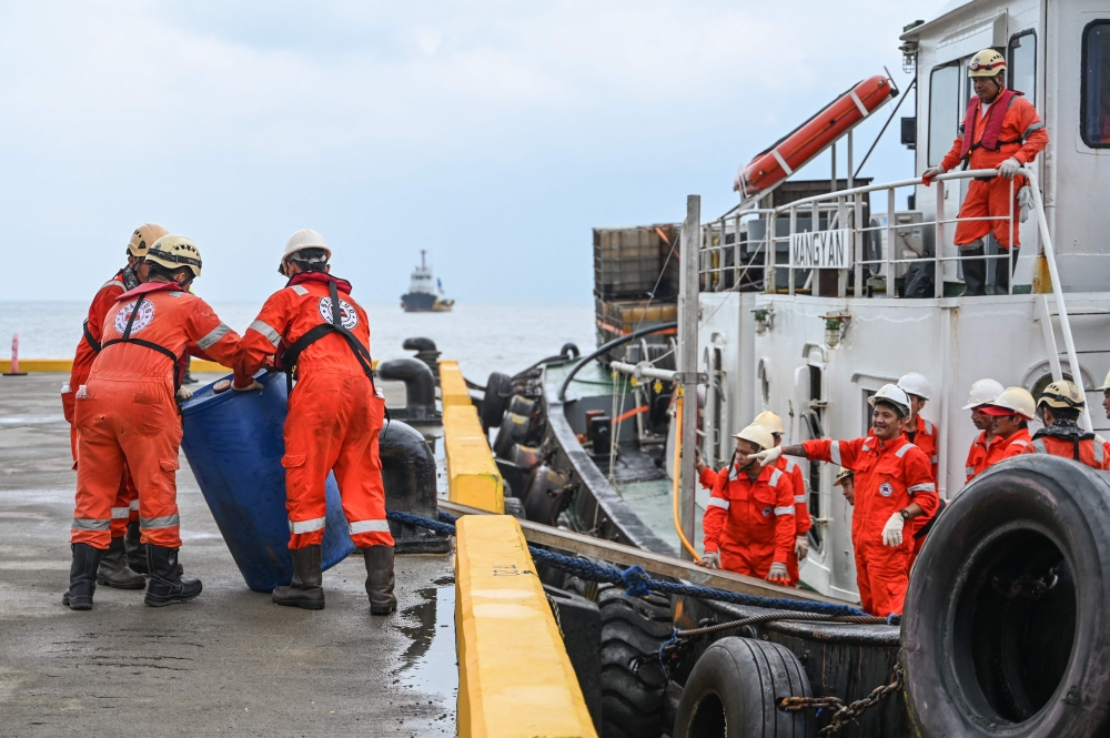 Crew of a private company loads a barrel of oil spill dispersant to be used in the oil spill response, at a port in Limay, Bataan on July 26, 2024. (Photo by Jam Sta Rosa / AFP)
 